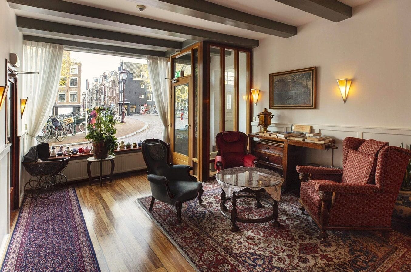 Beamed lounge with Persian rugs, wingback armchairs and a wide window onto the street