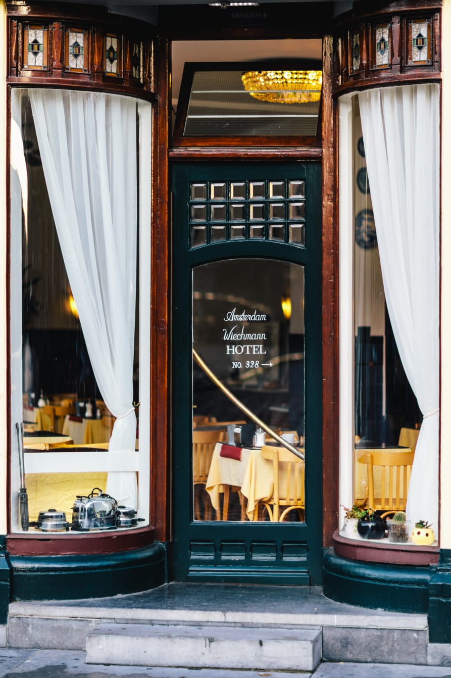 The hotel's green front door at No. 328, lettered Amsterdam Wiechmann Hotel, between two curved bay windows