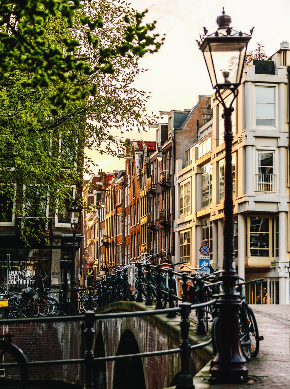 A canal-side street in Amsterdam, with a lamppost and moored bicycles